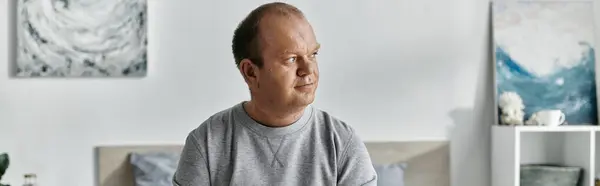 Чоловік з інклюзивністю сидить на ліжку, думаючи напередодні в світлій і повітряній кімнаті. — Stock Photo