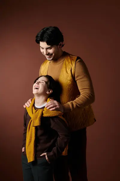 Un père et son fils partagent un moment de rire et d'affection sur fond brun. — Photo de stock