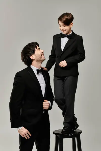 A father and son, both dressed in suits and bow ties, share a playful moment together. — Stock Photo