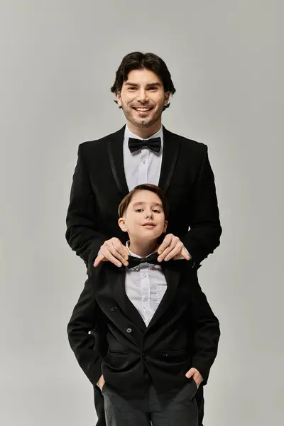 A father and son in formal attire, the father adjusting the sons bow tie. — Stock Photo