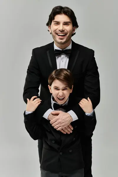 A father and son in formal wear share a moment of laughter and affection. — Stock Photo