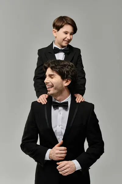 A father and son share a joyful moment, dressed in black tie attire. — Stock Photo