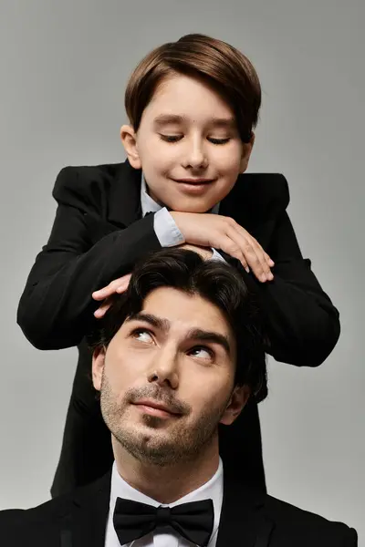 A young boy playfully places his hands on his fathers head, while the father looks up with a smile. — Stock Photo
