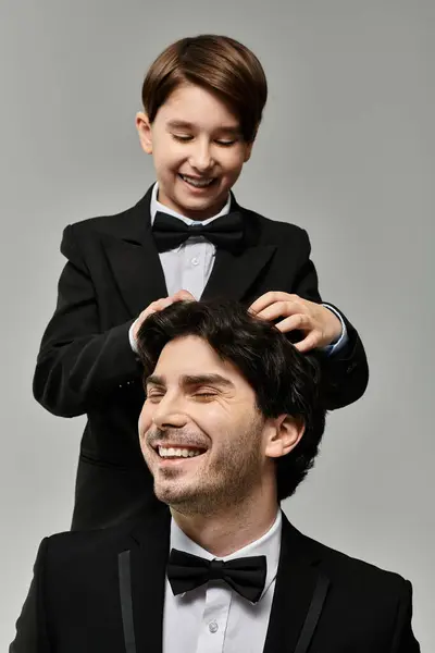 A father smiles contentedly as his son playfully ruffles his hair. — Stock Photo