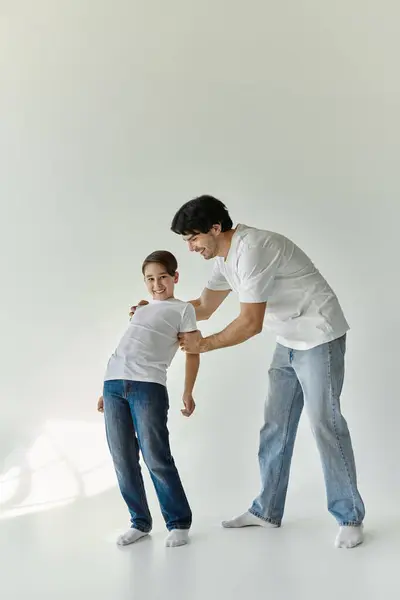 A father and son enjoy a playful moment together in a white room. — Stock Photo
