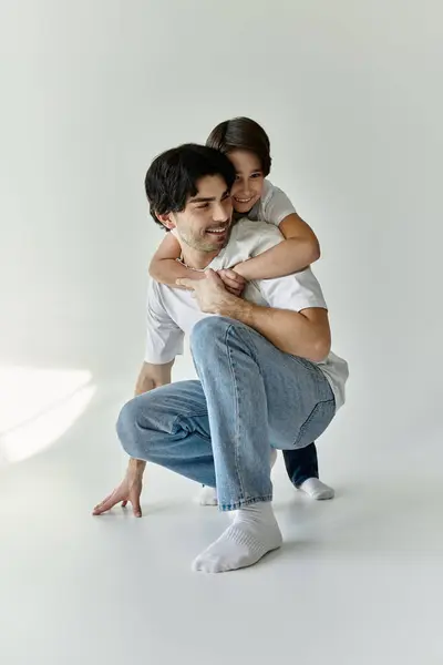 A father and son enjoy a playful moment indoors, with the son hugging his father from behind. — Stock Photo
