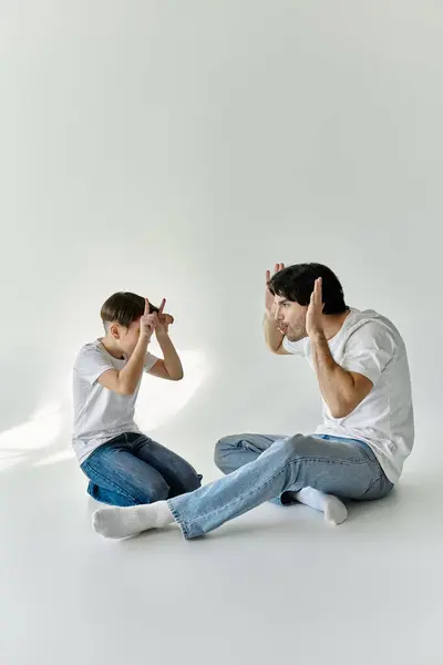 A father and son sit on the floor, playfully engaging in a lighthearted game. — Stock Photo