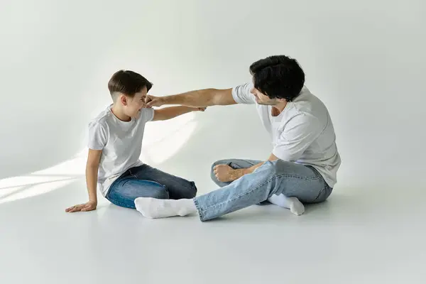 A father and his son sit on the floor, engaging in a playful moment. — Stock Photo