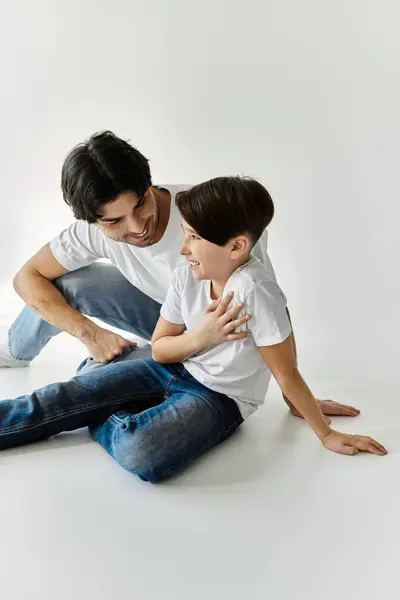 A father and son share a moment of laughter and connection while sitting on the floor. — Stock Photo
