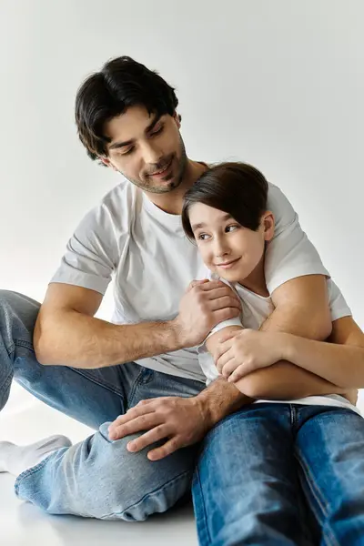 A father and his son sit together, the father lovingly embracing his son. — Stock Photo