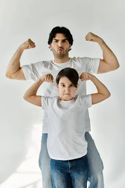 A father and son stand side-by-side flexing their muscles in a playful gesture. — Stock Photo