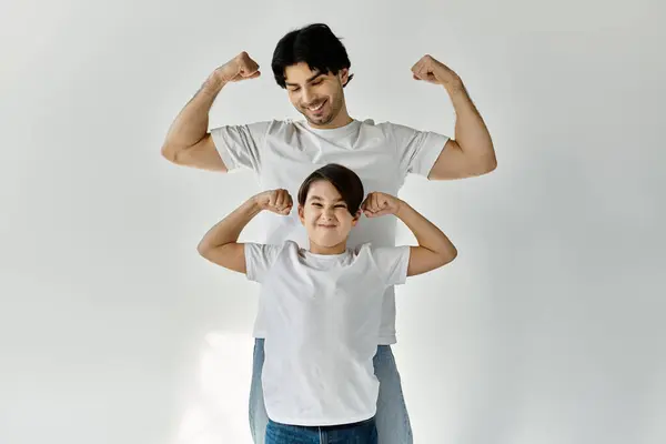A father and son playfully flex their muscles, capturing a tender moment of bonding and shared strength. — Stock Photo