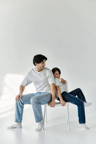 Un père et son fils partagent un moment ludique, assis sur une chaise blanche dans une pièce lumineuse. — Photo de stock