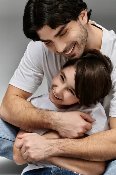 A father holds his son close, both smiling brightly. — Stock Photo