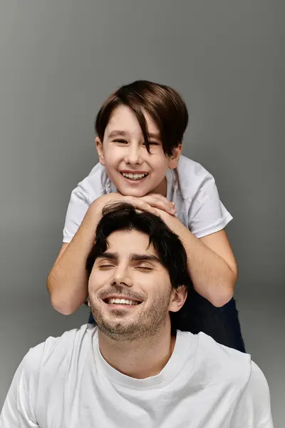 A father and son are laughing together against a grey background. — Stock Photo