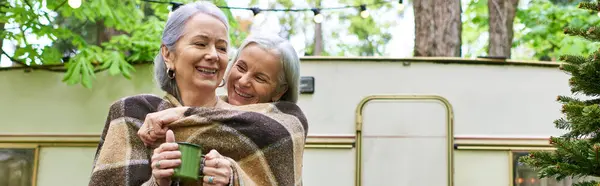 A lesbian couple enjoys a cozy moment together while camping in a green forest. — Stock Photo
