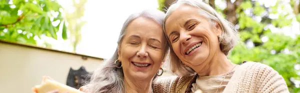 Two middle-aged women laugh together in a lush green forest. — Stock Photo
