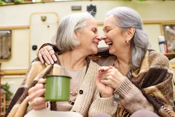 A lesbian couple smiles and holds hands while camping in the woods near their RV. — Stock Photo