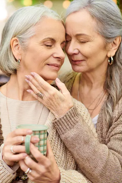 Two middle-aged women are captured in a moment of love and intimacy while camping in a lush green forest. — Stock Photo