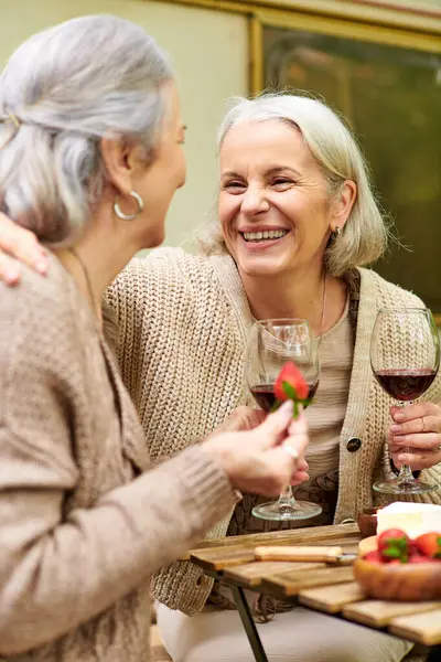Лесбийская пара наслаждается расслабляющим вечером кемпинг, смеясь и делясь вином. — стоковое фото