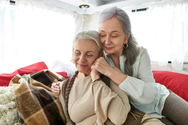 Two middle-aged lesbian women share a tender moment inside their camper van during a road trip. — Stock Photo