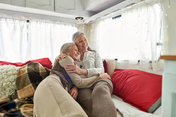 Un couple lesbien d'âge moyen s'embrasse dans un camping-car confortable pendant leur voyage sur la route. — Photo de stock
