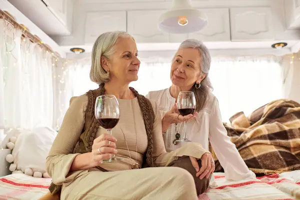 Two middle-aged women sit in a camper van, enjoying wine and conversation. — Stock Photo