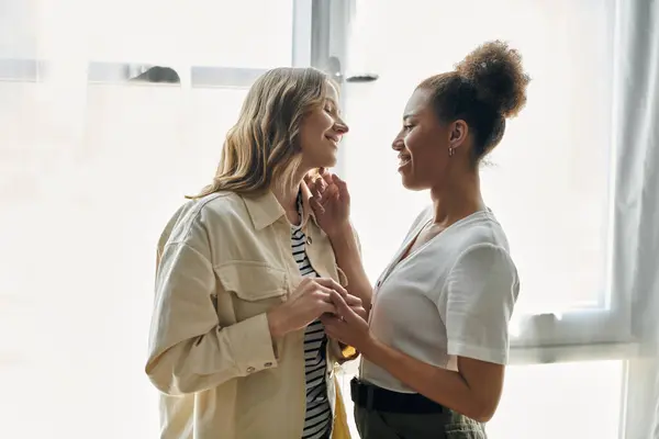 Una pareja lesbiana disfruta de un momento de intimidad en casa, bañada por la cálida luz del sol. - foto de stock