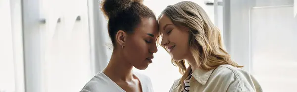 A diverse lesbian couple shares a tender moment, their foreheads touching in a sign of love and affection. — Stock Photo