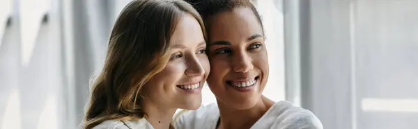 Two women, a lesbian couple, smile lovingly at each other in their home. — Stock Photo