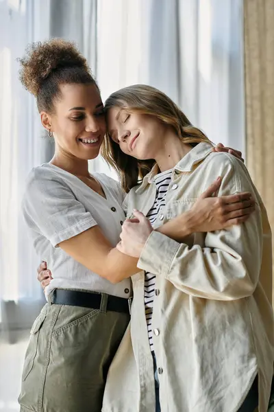 A lesbian couple in casual clothes embraces at home. — Stock Photo