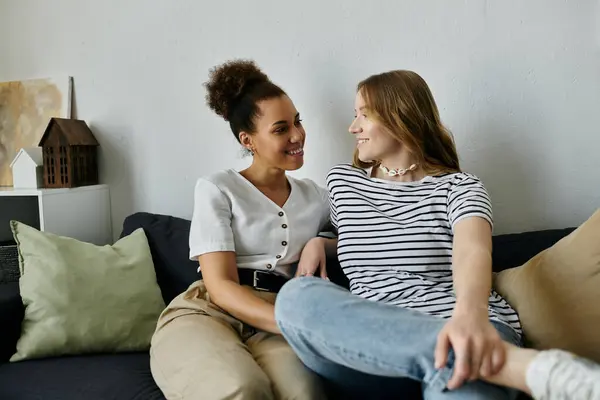 Two women cuddle on a couch and enjoy each others company. — Stock Photo
