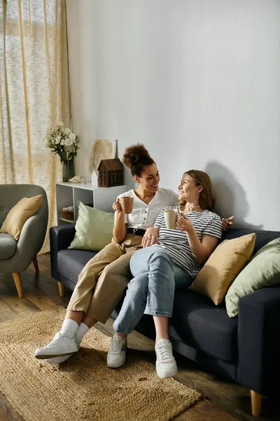 Two women relax on a couch, enjoying a cozy afternoon together. — Stock Photo