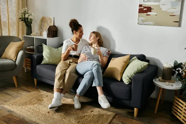 A lesbian couple relaxes together at home, sharing a drink and enjoying each others company. — Stock Photo