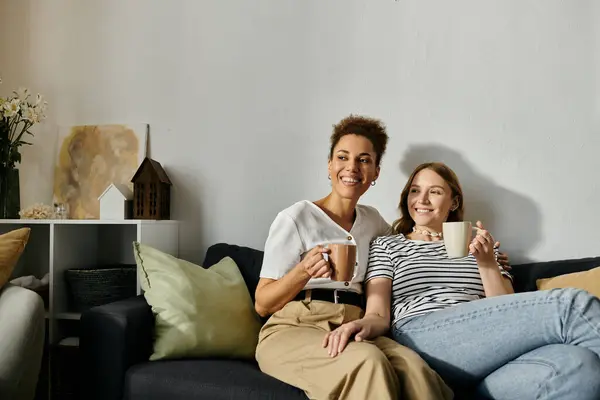 Un couple de lesbiennes se détend sur un canapé, partageant un café à la maison. — Photo de stock