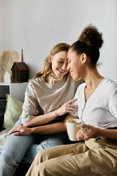 Dos mujeres están sentadas juntas en un sofá, sus frentes tocándose, sonriendo. — Stock Photo