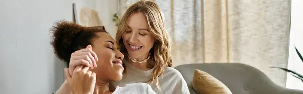 Two women, a lesbian couple, cuddle close at home, smiling and looking at each other lovingly. — Stock Photo