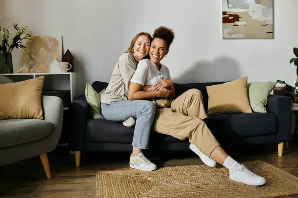 A lesbian couple shares a loving embrace while relaxing on a sofa. — Stock Photo
