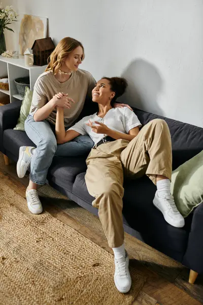 A lesbian couple shares a tender moment on a couch at home. — Stock Photo