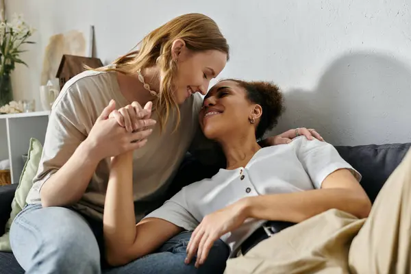 A lesbian couple shares a tender moment while sitting on a couch in their home. — Stock Photo