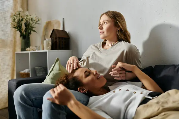 A lesbian couple relaxes together at home on a couch. — Stock Photo