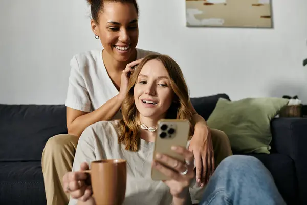 A diverse lesbian couple enjoys a relaxing afternoon at home, laughing together on the couch. — Stock Photo