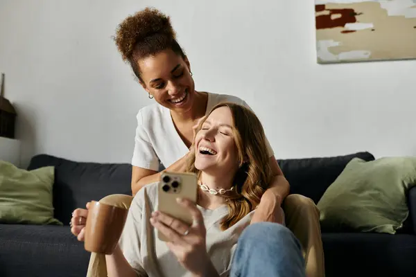 A diverse lesbian couple relaxes at home, laughing together while enjoying a moment of intimacy. — Stock Photo