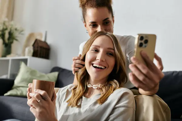 A diverse lesbian couple enjoys a relaxing afternoon at home, sharing a laugh and a warm beverage. — Stock Photo