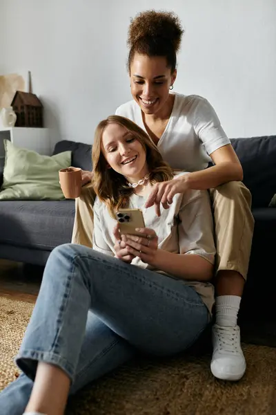 Two women, a lesbian couple, relax at home and look at a phone together. — Stock Photo