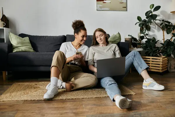 A lesbian couple relaxes at home, one using a laptop and the other looking at a phone. — Stock Photo