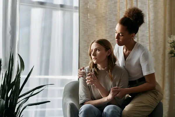 A lesbian couple sits together in their home, one comforting the other. — Stock Photo