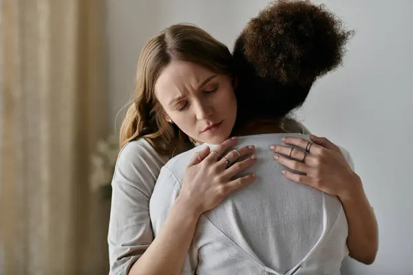 A diverse lesbian couple embraces in a warm, comforting hug at home. — Stock Photo