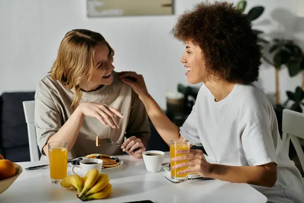 Two women, dressed casually, share a meal and laughter at home. — Stock Photo