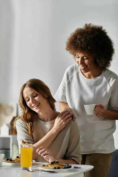 A diverse lesbian couple shares a loving moment while enjoying breakfast at home. — Stock Photo